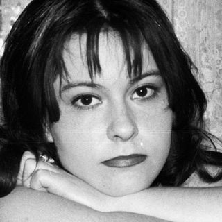 Black and white portrait of a young woman with arms crossed.