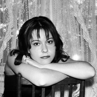 Black and white portrait of a young woman with arms crossed.