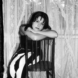 Here's a brief summary: Woman seated on chair, posing in black and white clothing.