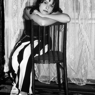 Here's a brief summary: Woman seated on chair, posing in black and white clothing.