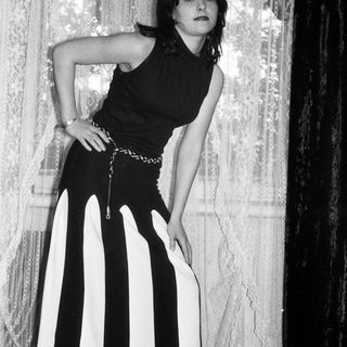 Woman in black top and striped pants poses for photograph.