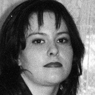 Woman in black top and striped pants poses for photograph.
