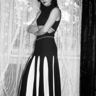Woman in a striped dress stands with arms crossed.