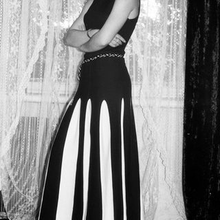 Woman in a striped dress stands with arms crossed.