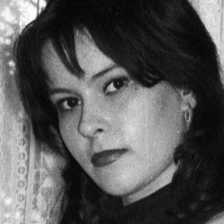 Woman in a striped dress stands with arms crossed.