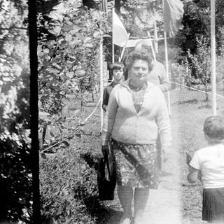 Here's a brief summary of the image: Black and white photo of people outdoors, possibly a park.