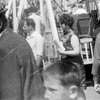 Vintage fairground scene with a Ferris wheel and people.