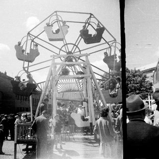 Vintage fairground scene with a Ferris wheel and people.