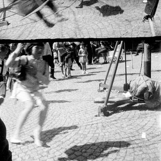 Blurry figures and playground equipment in a public space.