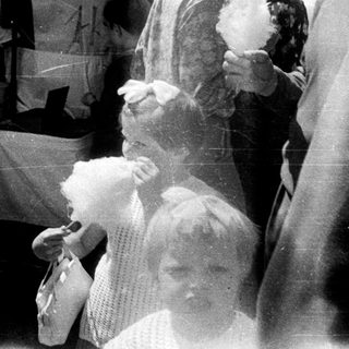 Here's a brief summary of the image: People line up for cotton candy at a fair.