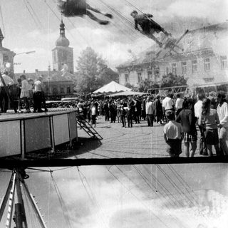 Crowd watches a trapeze artist perform outdoors.