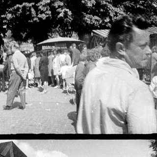 Crowded town square scene, people socializing and passing by.