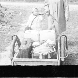 Person pulling a sled with a baby in a snowy landscape.