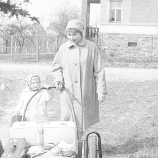 Person pulling a sled with a baby in a snowy landscape.