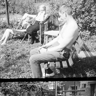 Here's a brief summary of the image: Two people relax in chairs, a man sits on a bench.