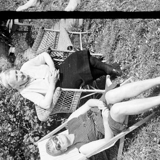Two women relaxing in chairs outdoors in a garden.