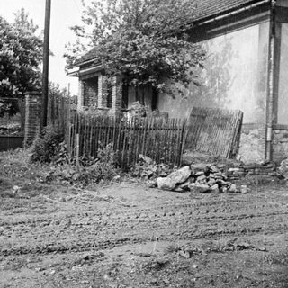 Dilapidated house with unfinished construction and overgrown land.