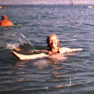 People swimming in the ocean with a cliff backdrop.