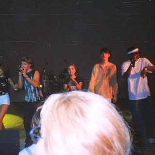 Concert crowd with performers on stage in the darkness.