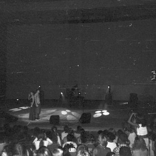 People watching performers on a stage with spotlights.