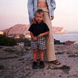Woman and child stand overlooking a coastal view.