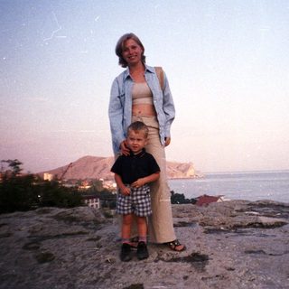 Woman and child stand overlooking a coastal view.