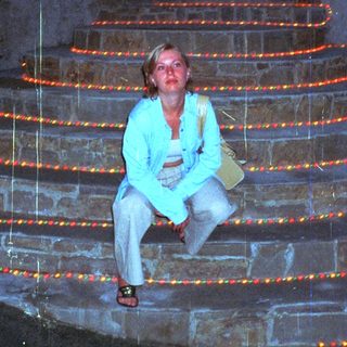 Woman sits on steps lined with candles at night.