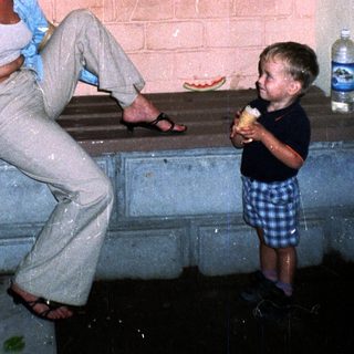 Woman and child sit on steps in a brick archway.
