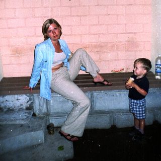 Woman and child sit on steps in a brick archway.