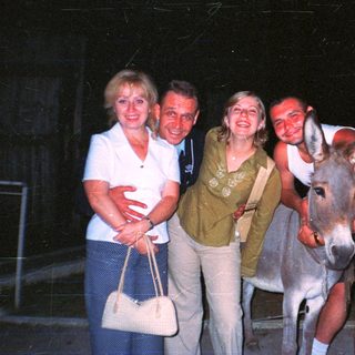Family posing with a donkey at night.