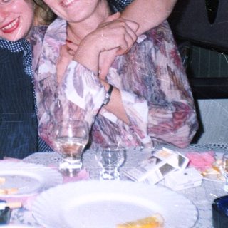 Four smiling women are grouped at a table.