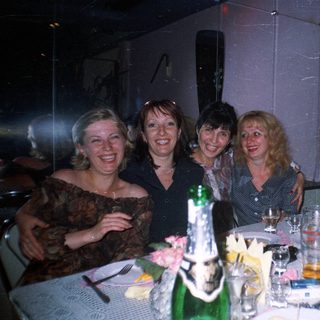 Four women are posing at a table with drinks.
