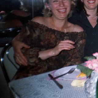 Four women are posing at a table with drinks.