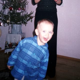 Boy running toward a woman near a small Christmas tree.