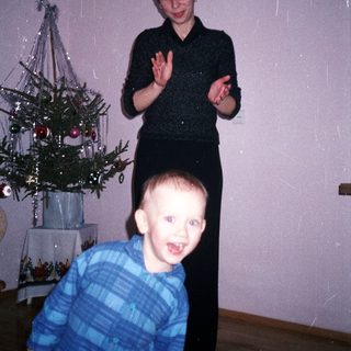 Boy running toward a woman near a small Christmas tree.