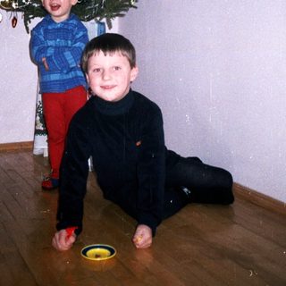 Here's a brief summary: Two boys play near a small, decorated Christmas tree.