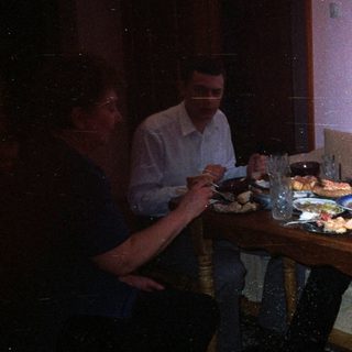 People are dining together at a table in a dimly lit room.