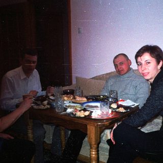 People are dining together at a table in a dimly lit room.