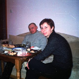 People are dining together at a table in a dimly lit room.