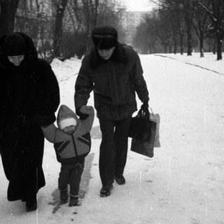 People walk on a snowy street with a child.