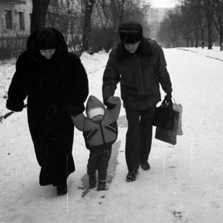 People walk on a snowy street with a child.