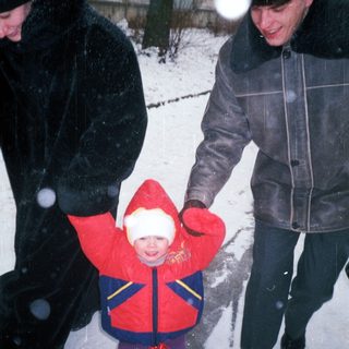 Child in winter coat is being carried through snow.