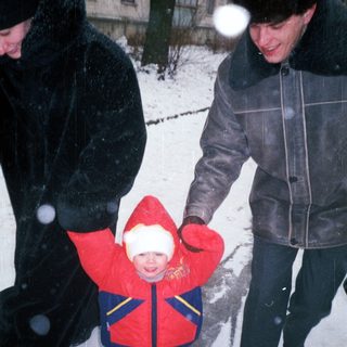 Child in winter coat is being carried through snow.