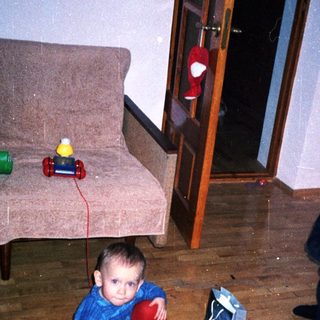 Two young boys play with toys on a rug.