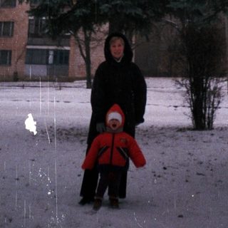 Snowy landscape shows a person and child walking outdoors.