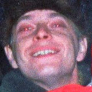 Man holds child, possibly ice skating, at night.