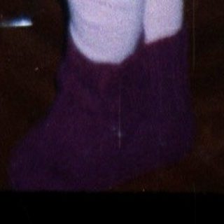 Child stands near a Christmas tree with tinsel.