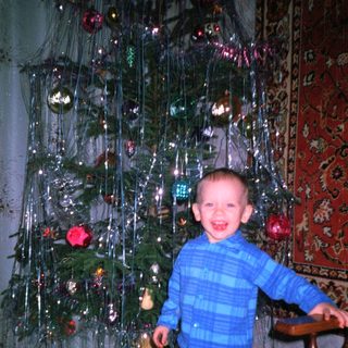 Boy smiles near a decorated Christmas tree.