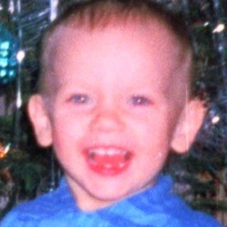 Boy smiles near a decorated Christmas tree.