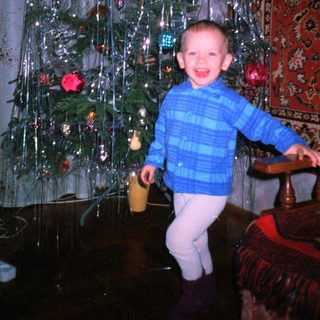 Boy smiles near a decorated Christmas tree.